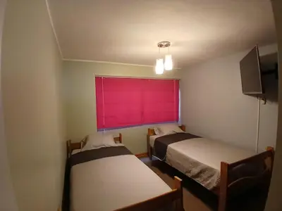 two beds in a room with a red window at Apartamento Ideal en Zona Céntrica in Lima