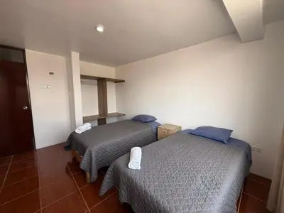a room with two beds in a hotel room at Hostal La Reserva - Pisco in Pisco