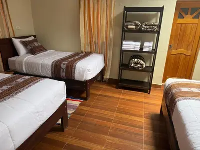 a room with two beds and a wooden floor at Huilka Mayu in Urubamba