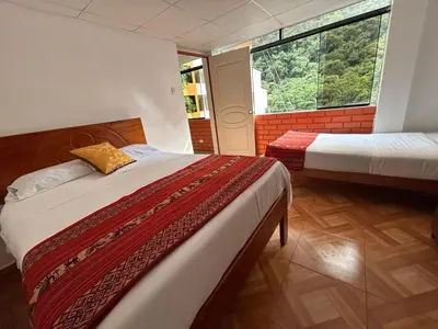 a bedroom with two beds and a large window at All sur departamento in Machu Picchu