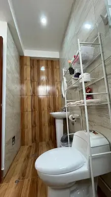 a bathroom with a toilet and a shelf above it at Departamento en Urubamba in Urubamba