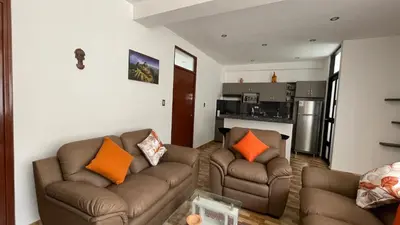 a living room with two couches and a kitchen at Departamento en Urubamba in Urubamba