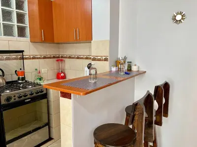 a kitchen with a counter with a stove and a table at Cozy & Centric Apartment in great location! in Cusco