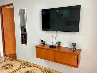 a flat screen tv on a wall with a wooden dresser at Cozy & Centric Apartment in great location! in Cusco