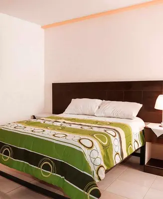 a bedroom with a bed with a green and yellow blanket at Hotel Bartol in Huancayo