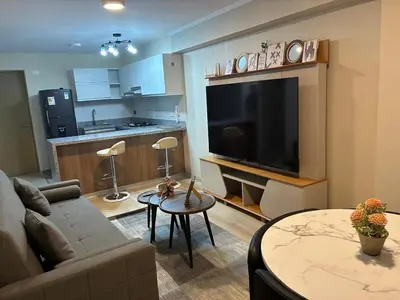 a living room with a couch and a large flat screen tv at Modern apartment overlooking Parque de las Aguas in Lima