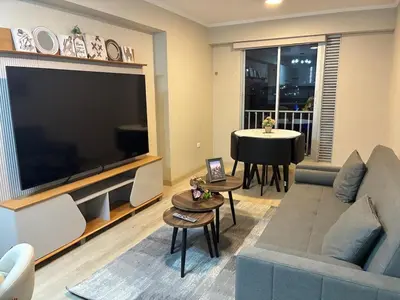 a living room with a large television and a table at Modern apartment overlooking Parque de las Aguas in Lima