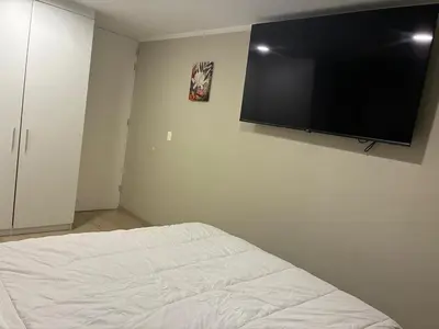 a bedroom with a bed with a flat screen tv on the wall at Modern apartment overlooking Parque de las Aguas in Lima