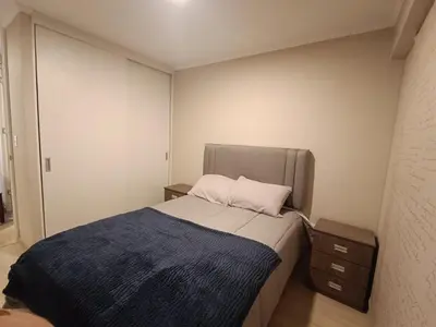 a small bedroom with a bed with a blue blanket at Comfortable apartment in Parque la Reserva in Lima