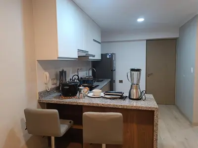 a kitchen with a counter with two chairs and a blender at Comfortable apartment in Parque la Reserva in Lima