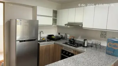 a kitchen with a stainless steel refrigerator and wooden cabinets at Cozy apartment overlooking Parque de las Aguas in Lima