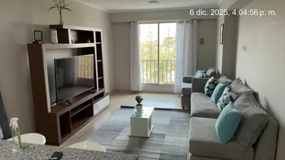 a living room with a couch and a television at Cozy apartment overlooking Parque de las Aguas in Lima