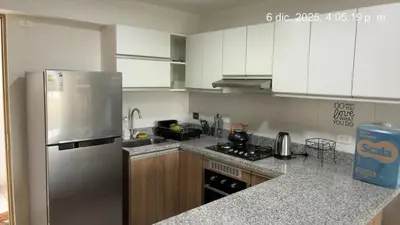 a kitchen with white cabinets and a stainless steel refrigerator at Cozy apartment overlooking Parque de las Aguas in Lima