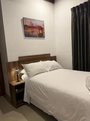 a bedroom with a white bed and a night stand at Serendipia City Comfort Suite 901 in Lima