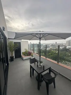 a table and chairs on a balcony with an umbrella at Luxury Duplex on the 15th Floor with Terrace in Lima