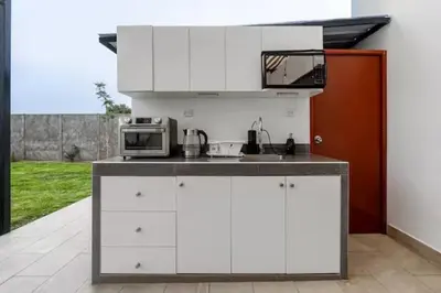a kitchen with white cabinets and a microwave and a sink at Huaral House Piscina y Terraza in Huaral