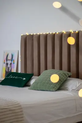 a bed with a wooden headboard and two green pillows at Huaral House Piscina y Terraza in Huaral