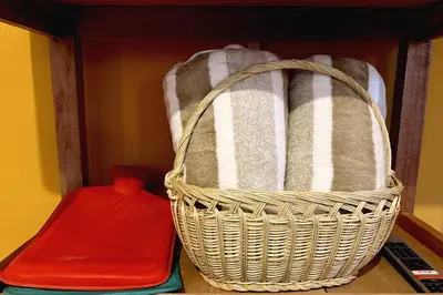a basket of towels on a shelf with a red container at Apartment with terrace and outdoor kitchen in Cusco