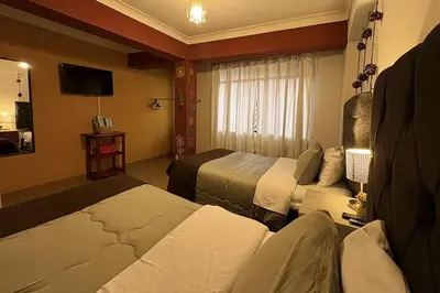 a hotel room with two beds and a television at Apartment with terrace and outdoor kitchen in Cusco