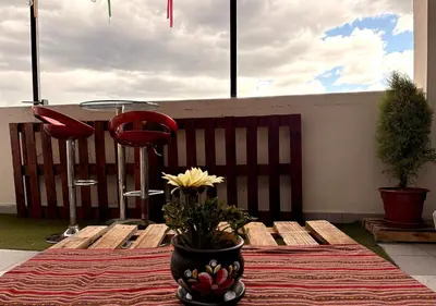 a table with a vase with a yellow flower in it at Apartment with terrace and outdoor kitchen in Cusco