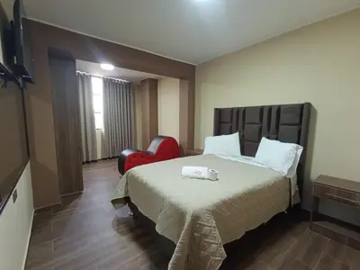 a hotel room with a bed and a red chair at Kapricho Wanka in Huancayo