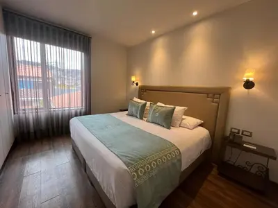 a bedroom with a large bed and a large window at Casa Esmeralda by Katari in Cusco