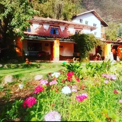 a house with a field of flowers in front of it at EColodge Ccatan in Urubamba