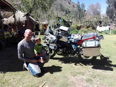 a man holding a child next to a motorcycle at EColodge Ccatan in Urubamba