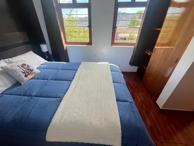 a bedroom with a blue bed with two windows at Legendary Rock Cusco Apartment in Cusco
