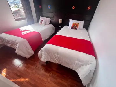 a bedroom with two beds with white and red sheets at Legendary Rock Cusco Apartment in Cusco