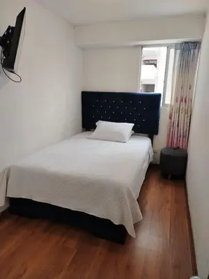 a bedroom with a bed with white sheets and a window at Departamento Executive 2BR Balcón Frente al Mall Santa Catalina in Lima