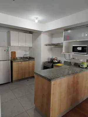 a kitchen with wooden cabinets and a counter top at Departamento Executive 2BR Balcón Frente al Mall Santa Catalina in Lima