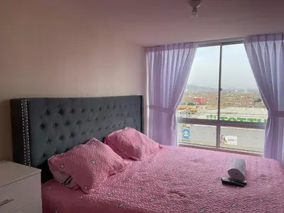 a bedroom with a pink bed with a large window at New Apartment near the airport with parking in Lima