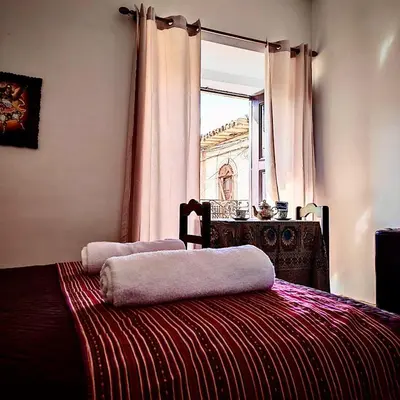 a bedroom with a bed and a window with a building at Tres Reyes Hospedaje in Cusco