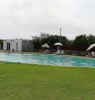 a swimming pool with chairs and umbrellas on the grass at Asia soleil in Asia