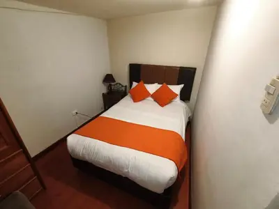 a bedroom with a bed with orange and white pillows at Mayu House Inn V en el Centro Historico in Cusco
