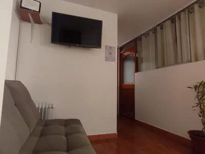a living room with a couch and a tv on the wall at Hermozo Cusco-Calle Fierro in Cusco