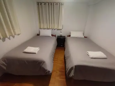 two beds in a small room with white sheets at Hermozo Cusco-Calle Fierro in Cusco