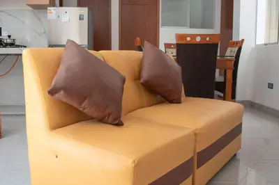 a yellow couch with two brown pillows on it at Apart Hotel Alojate Kaypi in Ayacucho