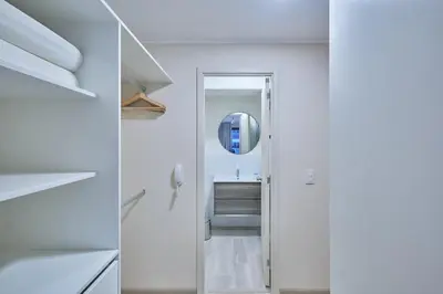 a white bathroom with a mirror and a sink at Larco Prime Suites - Pool, Gym & Coworking in Lima