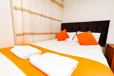 a bed with orange and white pillows on it at Mayu House Inn IV en el centro histórico in Cusco
