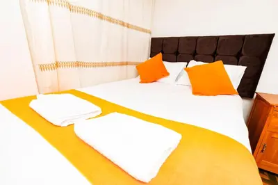 a bed with orange and white pillows on it at Mayu House Inn IV en el centro histórico in Cusco