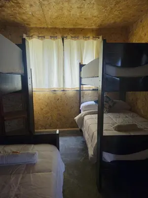 a room with three bunk beds and a window at La Montaña Lodge - Oxapampa in Oxapampa