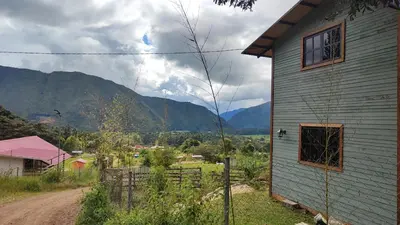 a house on a dirt road with mountains in the background at La Montaña Lodge - Oxapampa in Oxapampa