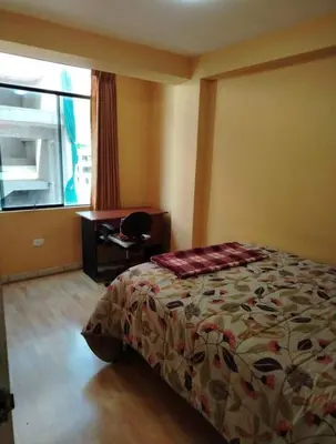 a bedroom with a bed and a desk and a window at Residencial Huancaro Apartament in Cusco