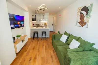 a living room with a green couch and a kitchen at BSR Brand New Apt Near Larcomar w/ Parking & Gym in Lima