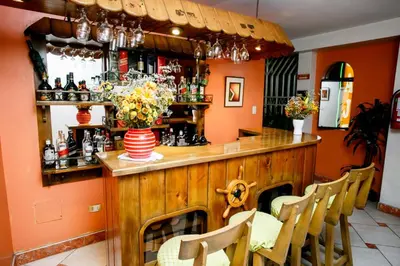 a bar in a restaurant with orange walls and chairs at Hospedaje El Remanso in Lima