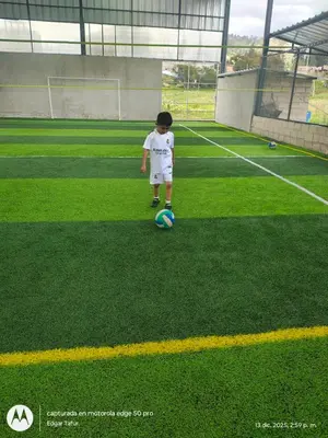 a young boy playing with a soccer ball on a field at Nuevo campo verde eirl in Lima