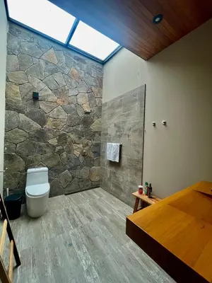 a bathroom with a toilet and a stone wall at Country House in Azpitia Villa las Leñas in Santa Cruz de Flores