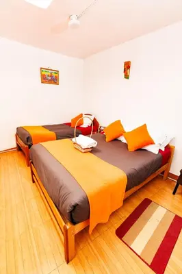 a bedroom with two beds with orange and brown sheets at Mayu House Inn I a minutos de la plaza in Cusco